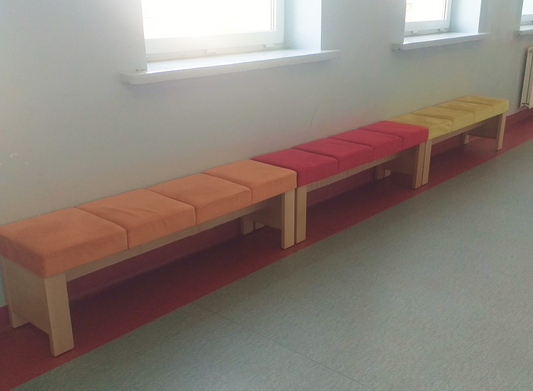 Ławki szkolne NORA IV buk naturalny z tapicerką Focus orange i red na szkolnym korytarzu w Tomaszowie Mazowieckim